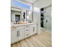 Modern bathroom featuring double sinks, white cabinetry, a large walk-in shower, and plank flooring at 10709 Hunters Woods Pl, Las Vegas, NV 89134