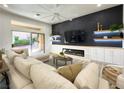 Modern living room with a large sectional couch, fireplace, entertainment center, and sliding glass door to the backyard at 10709 Hunters Woods Pl, Las Vegas, NV 89134