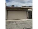 View of the garage door of a one-story home with a black metal gate to the right at 1203 Mews Ln, Las Vegas, NV 89101