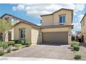 Tan two-story home with two-car garage, brick driveway, and desert landscaping at 2877 Sweeping Palm Rd, North Las Vegas, NV 89086