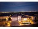 Night shot of a charming home with a brick-accented two-car garage and lush landscaping against a city view at 3000 Dusky Willow Ln, Las Vegas, NV 89138