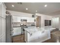 An open kitchen features stainless steel appliances, a center island with marble countertops, and hardwood floors at 6329 Sterling Ranch Way, North Las Vegas, NV 89081