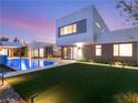 Modern backyard boasts artificial turf, an in-ground pool with a sun shelf, and a covered patio at 7385 Heron Canyon Ct, Las Vegas, NV 89117