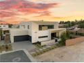 Stunning modern home featuring a three car garage, xeriscaped yard, and vibrant sunset backdrop at 7385 Heron Canyon Ct, Las Vegas, NV 89117