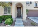 Close-up of the front door entrance with arched porch and manicured landscaping at 10135 Haymarket Peak Ave, Las Vegas, NV 89166