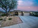 Single-story home with stone accents, landscaped yard, and an attached two-car garage under a moonlit sky at 10309 Canyon Valley Ave, Las Vegas, NV 89145