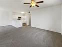 A well lit living room with neutral colored walls and gray carpet leads into the open concept kitchen at 1405 S Nellis Blvd # 2087, Las Vegas, NV 89104