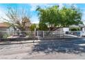 Street view of a cozy single-story home featuring a metal fence, mature trees, and front yard landscaping at 2732 Johannson Ln, Las Vegas, NV 89115