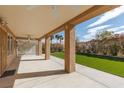 Inviting covered patio with ceiling fans and decorative columns overlooking the artificial lawn at 3032 Bonnie Rock Dr, Las Vegas, NV 89134