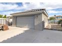Detached garage with a gray door, offering additional parking or storage space, with a walkway beside it at 3684 Mooncrest Cir, Las Vegas, NV 89129