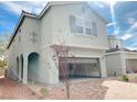 Light-grey two-story house with an open garage and desert-landscaped front yard with an arched entryway at 4274 Tarim St, Las Vegas, NV 89147