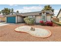 Well-maintained single-story home with decorative rock landscaping, flowers, and a blue garage door at 4813 Canadian Dr, Las Vegas, NV 89130