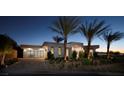 Modern home exterior with a three-car garage, desert landscaping, and palm trees at 661 Dragon Peak Dr, Henderson, NV 89012