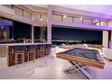 Elegant living room with a bar and pool table, seamlessly blending indoor and outdoor entertainment spaces at 661 Dragon Peak Dr, Henderson, NV 89012