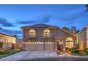 Charming two-story home showcasing arched windows, a three-car garage, and well-maintained landscaping at 8204 Antler Pines Ct, Las Vegas, NV 89149