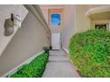 A front entrance with a white door, complemented by lush green bushes and stone walkway at 8221 Crow Valley Ln, Las Vegas, NV 89113