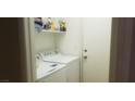 Bright laundry room featuring modern washer and dryer, complemented by upper shelving for convenient storage solutions at 857 Lantham Pl, Las Vegas, NV 89110