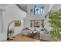 Bright, open living room with high ceilings, large windows, comfortable seating, and elegant decor with an eye-catching lamp at 8838 Spanish Mountain Dr, Las Vegas, NV 89148