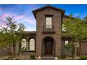 Inviting two-story home featuring brick and stucco, manicured landscaping, and an arched front entryway at 11944 Dolcemente Ln, Las Vegas, NV 89138