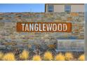 Community entrance sign reads Tanglewood in chrome letters mounted on a stone wall, landscaped with desert plants at 1634 Deep Valley Ave, North Las Vegas, NV 89084
