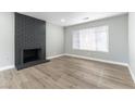 View of a bright living room with wood-look floors, a decorative fireplace, and a large window at 2346 Roan Ave, Las Vegas, NV 89119