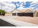 Attractive single-story home with two-car garage, lush desert landscaping, and mature palms under a partly cloudy sky at 3630 Daisy Field Dr, North Las Vegas, NV 89032