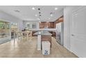 Open kitchen with stainless steel appliances, brown cabinets, and an island with a sink at 5731 Sedona Springs St, North Las Vegas, NV 89031