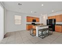 A well-lit kitchen featuring wood cabinets, granite countertops, a breakfast bar, and stainless steel appliances at 6130 Yuzu Pl, Las Vegas, NV 89122