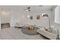 Bright living room with tile flooring, modern decor, and two comfortable chairs flanking a golden accent table at 6130 Yuzu Pl, Las Vegas, NV 89122