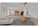 Open-concept living room showing the kitchen area, tile flooring, ceiling fan, and lots of natural light at 6130 Yuzu Pl, Las Vegas, NV 89122