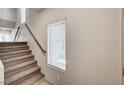 Carpeted staircase with wooden handrail, illuminated by a window, providing access to the upper levels at 8087 Carpenter Creek Ave, Las Vegas, NV 89113