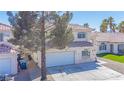 Charming stucco home featuring a red tile roof, arched entryway, and a spacious two-car garage at 8753 Fountain Island Dr, Las Vegas, NV 89147