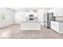 Modern kitchen featuring white cabinets, stainless steel appliances, an island with a sink, and neutral tile flooring at 9198 Rolling Sky Dr, Las Vegas, NV 89178