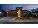 Charming single-story home featuring a well-manicured front yard, desert landscaping, and an attached two-car garage at dusk at 10385 Kern Ridge St, Las Vegas, NV 89178