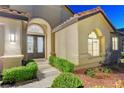 Close up of home's entryway with ornate double doors and lush, green landscaping at 3091 Via Del Corso, Henderson, NV 89052
