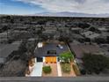Aerial view of a single story home featuring modern desert landscaping, a black roof and a freshly paved driveway at 6320 Dayton Ave, Las Vegas, NV 89107