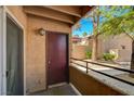Exterior balcony view showcasing a secure brown front door, siding, and beautiful desert foliage at 9325 W Desert Inn Rd # 143, Las Vegas, NV 89117