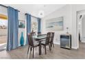 Dining room featuring modern chandelier, glass table, and blue accent drapes at 9445 Grand Mesa Dr, Las Vegas, NV 89134