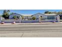 Street-level front view of the home featuring a decorative privacy fence, xeriscaping, and modern garage door at 7575 Coley Ave, Las Vegas, NV 89117