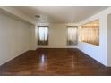 Open living area featuring hardwood floors, neutral paint, and large windows with decorative curtains at 7611 Avila Beach Ave, Las Vegas, NV 89113