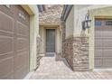 Exterior of a home featuring stone accents, a front door, and a two-car garage at 8732 Kendall Brook Cir, Las Vegas, NV 89149