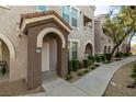 View of the home's entryway featuring a light colored door, lush landscaping, and decorative arches at 10001 Peace Way # 2228, Las Vegas, NV 89147