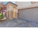 Close-up of a home's two-car garage with brick accents and a brick driveway at 10713 Noble Mesa Ave, Las Vegas, NV 89166