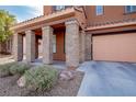 This home's facade includes a covered front porch with stone pillars and a two-car garage with a concrete driveway at 1125 Via Canale Dr, Henderson, NV 89011