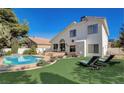 An inviting backyard with a sparkling pool, lush green lawn, and comfortable lounge chairs at 2714 Cricket Hollow Ct, Henderson, NV 89074