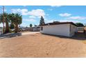 Side view of the house, showing driveway, desert landscaping, mature trees, and gated yard at 2825 Hickey Ave, North Las Vegas, NV 89030