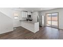 Modern kitchen featuring stainless steel appliances, a peninsula island, and hardwood flooring at 6270 Blood Lily Ave, Las Vegas, NV 89122