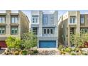 Contemporary home with a blue garage door, professionally landscaped front yard, and modern architectural details at 8016 Carpenter Creek Ave, Las Vegas, NV 89113