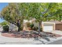 Inviting single-story home with desert landscaping, a two-car garage, and mature shade trees enhancing curb appeal at 1945 Trail Peak Ln, Las Vegas, NV 89134