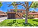 Two-story condo building with personal garages, well-kept lawn, and red tile roof at 250 Shadybrook Ln # D, Las Vegas, NV 89107